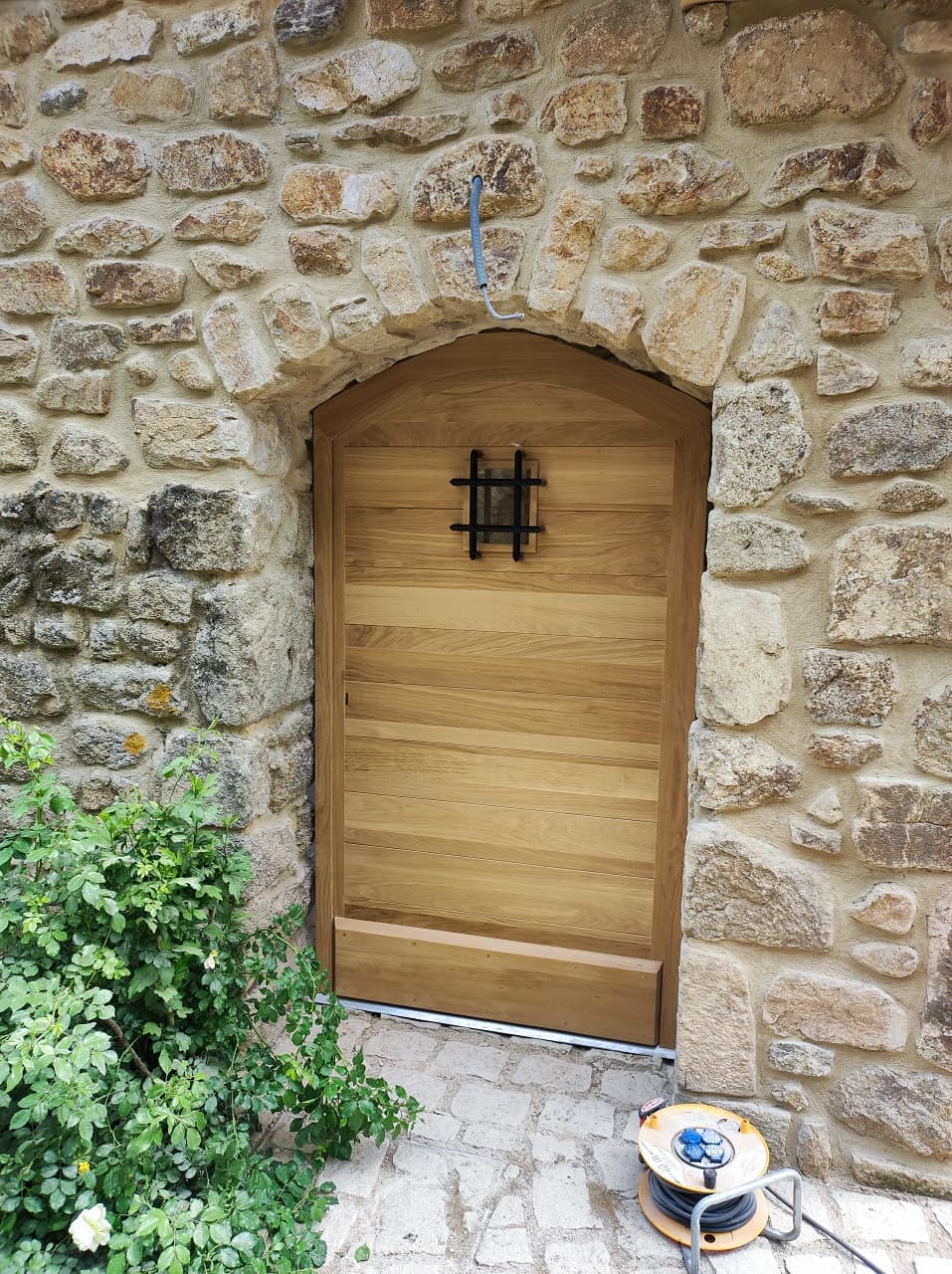 Installation d'une porte cintrée en bois dans un vieux batiment en pierres